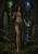 Red-haired woman with a glowing staff and smoking bowl stands among carved stones in a moonlit grove.
