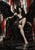 Dark-haired woman seated on a black throne with large black wings, red streaks on a pale distressed wall, and dark reflective steps.
