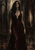 Long-haired woman with ornamental tattoos wearing a dark floor-length gown against a distressed stone-like background.
