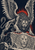 Snarling winged lion-like beast crouches above a second lion face amid dark angular rocks and red rays.