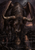 Horned, dark-furred winged bull-like creature standing beside shallow water with a visible reflection.