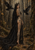 Crowned woman in a long black train looks back in a forest, framed by two flying black birds.