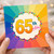 65th Birthday Card, Colourful Rainbow Sunburst Design