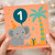 1st Birthday Card - Cute Elephant with Party Hat and Number 1 Balloon, Jungle Theme with Gift and Palm - For Baby Boy or Girl