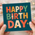 Happy Birthday Card - Bold Colour Block Letters with Flowers and Star on Teal, Fun Typographic Design for Him, Her, Friend, Mum, Dad or Colleague