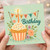 Happy Birthday Card - Cute Cupcake with Candle, Colourful Sprinkles, Floral Details and Bunting Design