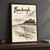 Bamburgh, England travel poster full-bleed print styled in Black frame / charcoal wall; frame and props not included