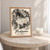 Predjama Castle cliff facade full-bleed print styled in Oak frame / bedside table; frame and props not included