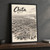 Chita city view full-bleed print styled in Black frame / charcoal wall; frame and props not included