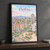 Pristina city view full-bleed print styled in Black frame / charcoal wall; frame and props not included