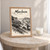 Mombasa city view full-bleed print styled in Oak frame / bedside table; frame and props not included