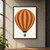 Upright hot-air balloon with alternating ochre and brick-red panels, dark seams, and a small blue-gray basket on a pale background.; frame shown for styling only