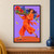 Smiling adult dancer in an orange-red outfit steps across a terracotta floor with a shoulder-height tray of red and blue flowers against lilac.; frame shown for styling only
