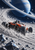 Red-orange open-wheel lunar racer with a helmeted driver powers through dust and rocks beneath a huge ringed planet.