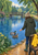 Two mallards and a visitor beside a rainy park pond, with a yellow raincoat on a bench, rippling water, trees, and a footbridge.