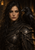 Dark-haired woman in weathered dark armor with a large black raven close beside her face.