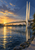 Pale cable-stayed footbridge with twin pylons crossing a reflective river at sunset, with small pedestrians and a golden horizon.