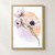 Three pale pink and lilac flowers with dark centers on curved stems, set over overlapping apricot and lilac shapes on white.; frame shown for styling only