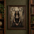 Seated black-haired woman in dark gothic clothing beneath branching antlers against a pale distressed wall.; frame shown for styling only