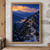 Several amber-lit cabins sit on a snowy forested mountain ridge above a lake, beneath glowing apricot clouds and a blue-hour sky.; frame shown for styling only