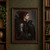 Red-haired woman in profile wearing dark feathered clothing and shoulder armor beside a black raven.; frame shown for styling only