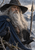 Bearded, cloaked figure with a spear and two ravens against snowy mountains and a low sun.