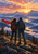 Two hikers seen from behind at a rocky mountain overlook during sunrise, one wearing a red scarf that streams left.