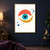 Stylized eye with a turquoise iris framed by coral and ochre curves and a path of cobalt dots on warm white.; frame shown for styling only