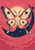 Four-winged moth perched on a dark diagonal crescent beneath a hanging glass orb, stars, and clouds in a rose-pink sky.