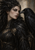 Woman in black feathered attire with bronze ornaments facing a large raven against a warm gray background.
