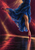 A dancer's lower body in a flowing blue skirt, with a fuchsia pointed shoe touching a reflective dark stage.