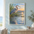 A blue-gray heron stands with one leg raised beside reflective marsh water, reeds and a warm sunrise.; frame shown for styling only