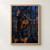Close portrait of an alert black-and-tan Doberman wearing a blue collar with a crescent charm in front of a rainy greenhouse window.; frame shown for styling only