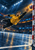 Adult male handball goalkeeper diving toward a ball near a goalpost in a blue-lit indoor arena.