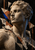 Pale stone bust turned left against a dark background with fractured cream, rust, charcoal, and vivid blue shapes.