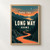 Ivory “TAKE THE LONG WAY HOME” lettering over a winding coral road through a dark pine valley toward water, a low sun, and a crescent moon.; frame shown for styling only