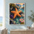 Large orange five-armed sea star on dark tidepool rocks, with anemones, reflective water and distant sunset headlands.; frame shown for styling only