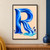 Large capital R formed from flowing cobalt and navy bands, spilling toward a turquoise pool on a pale peach background.; frame shown for styling only