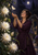Adult woman in a dark plum dress looks up at a pale moth hovering above her cupped hands, with white flowers and a moonlit garden path.