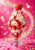 A strawberry-topped vanilla sundae in a clear glass, surrounded by a sweeping arc of colorful sprinkles against pink.