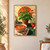A potted basil plant and a hand reaching into its foliage sit above a bowl of red tomato soup, with tomatoes, garlic, a bottle, and cloth on a dark green table.; frame shown for styling only