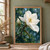 Large white magnolia with layered petals and visible stamens, an unopened bud, glossy leaves, branch, and water droplets.; frame shown for styling only