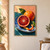A cut blood orange sits before a whole orange on a blue plate, with green leaves and curling peel against a peach wall and teal tabletop.; frame shown for styling only