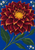 Large burgundy-red dahlia with a golden-yellow center against cobalt blue, surrounded by green stems, broad leaves, and small white star-shaped flowers.