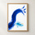 Broad cobalt-blue brushstroke arches over an aqua pigment pool and scattered droplets, with a small ochre accent on a white background.; frame shown for styling only