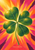 A large green four-leaf clover against radiating marigold, orange, coral, pink, and plum sunburst shapes, with “Clover in the Sun” at the bottom.