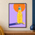 Clear bottle of golden citrus soda with a citrus slice and curled peel, in front of an orange sun on lilac with an indigo shadow.; frame shown for styling only