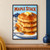 Pancake stack topped with butter and maple syrup, with a fork lifting a bite and blueberries behind, beneath MAPLE STACK lettering.; frame shown for styling only