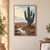 Tall branching ribbed cactus beside a reflective pool in a rocky desert, with distant mountains and pale sky.; frame shown for styling only