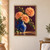 Three peach-orange dahlias and glossy green leaves rise from a cobalt-blue pitcher against a plum wall and warm tabletop.; frame shown for styling only